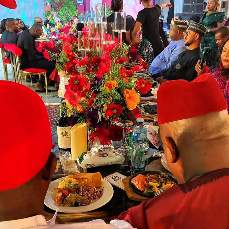 A long banquet table dressed with red floral centrepieces at a milestone birthday