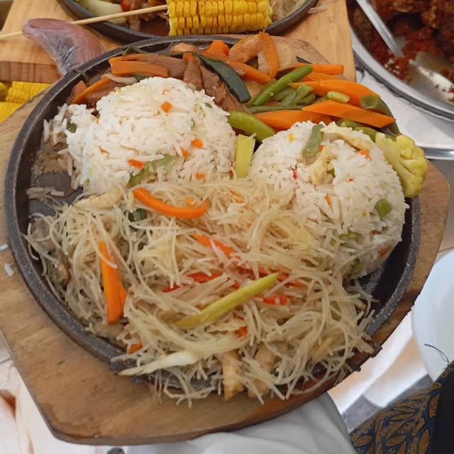 Sizzling platters of rice, noodles, vegetables and grilled corn on a buffet